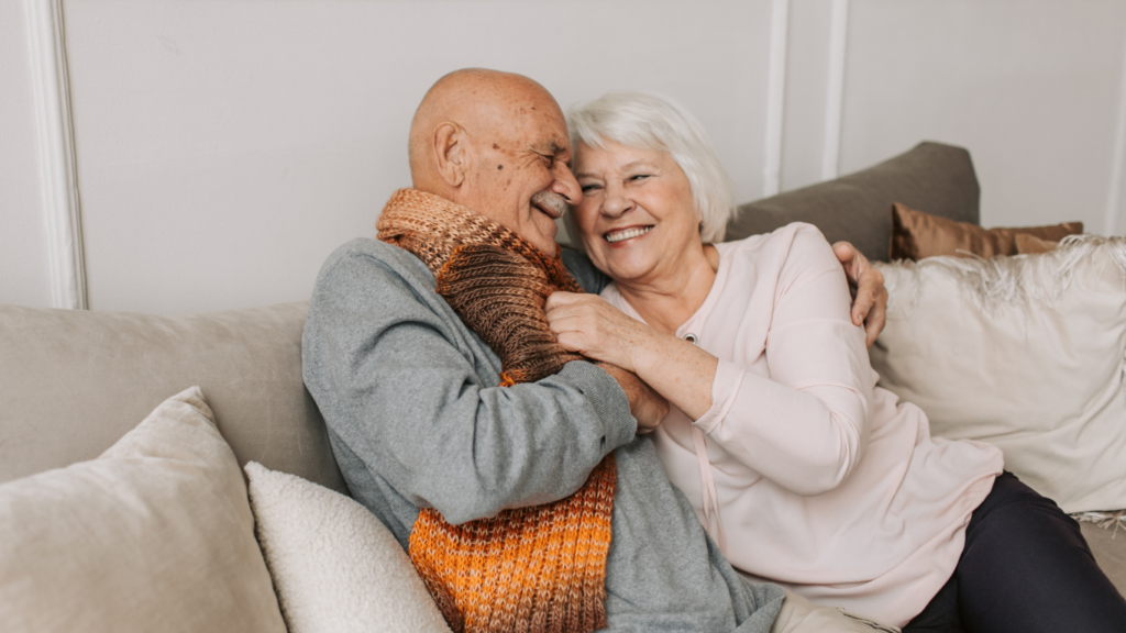 A healthy mature couple cuddles on a couch; the woman is no longer in pain because she's using Marodyne to improve her bone density.