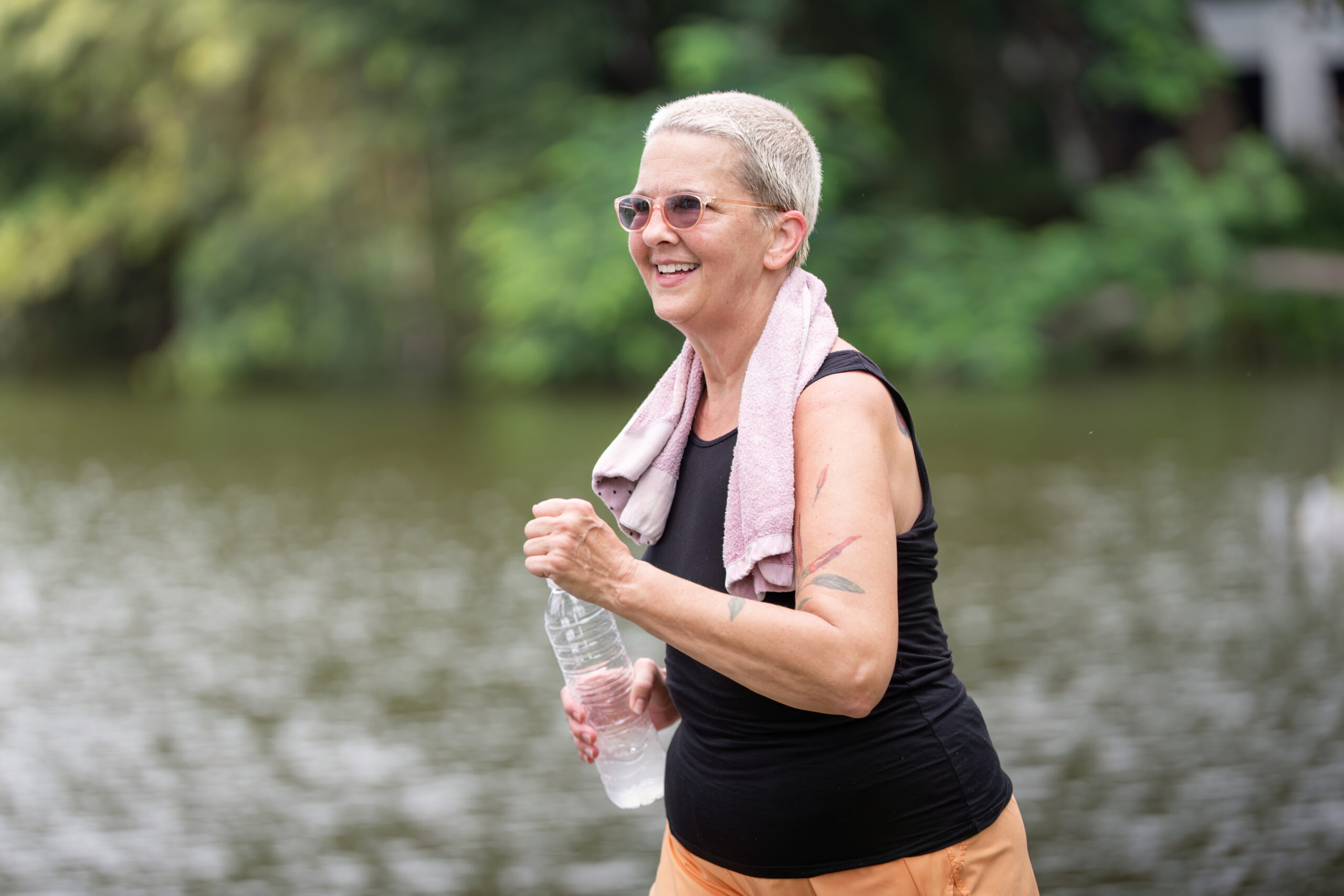 Active senior woman jogging outdoors with water bottle, supporting bone health through regular exercise