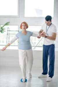 During the exercise. Pleasant sportive woman holding her coaches hand while doing the exercise